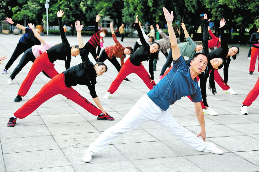 在元江县太阳城广场，社会体育指导员李磊正在带领群众做健身操。