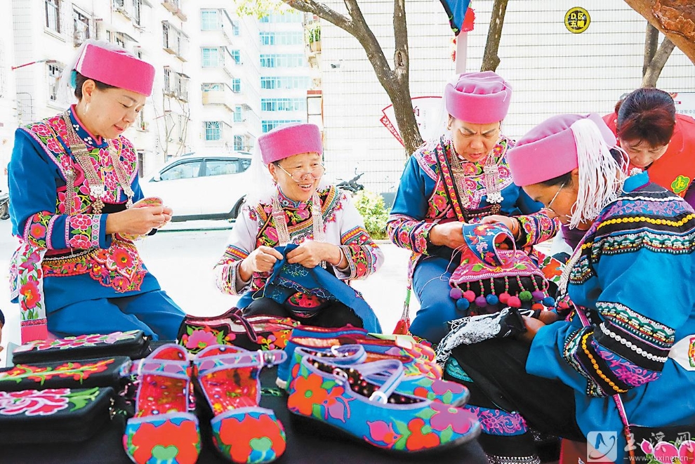 峨山县双江街道练江社区工会服务站外，小区住户聚在一起边刺绣边聊天。